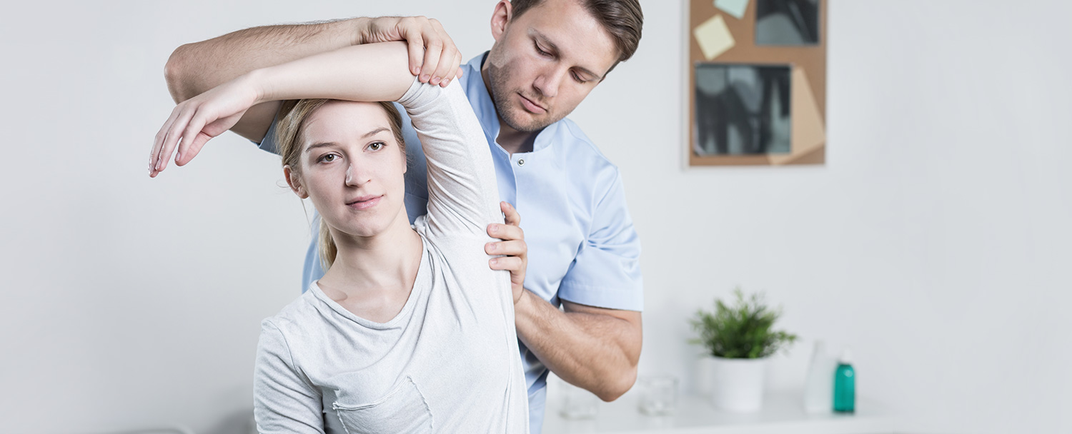 chiropractor adjusting a woman's shoulders during corrective exercises for physical therapy